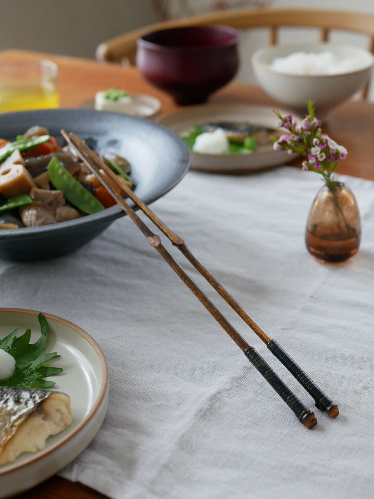 公長斎小菅の黒竹取り箸が皿とスプーンと共にテーブルに配置された写真