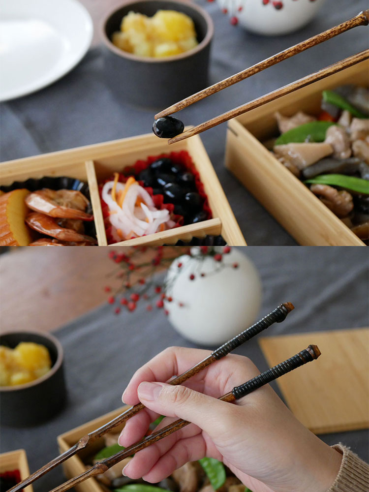 黒竹と籐で仕上げられた公長斎小菅の26cmおもてなし用黒竹取り箸が、食卓のテーブルウェアと共に美しくセットされている様子