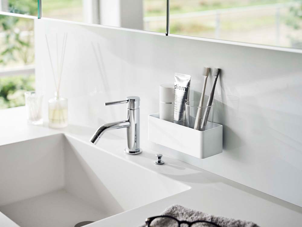 ホワイトのフィルムフックラックが浴室の洗面台カウンターに取り付けられており、シンクや蛇口と共に配置されています。