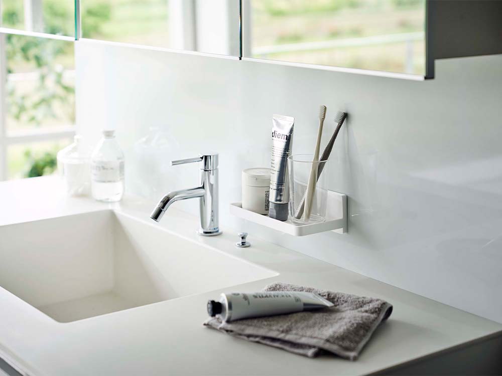 白色のフィルムフックトレーが設置されたバスルームの洗面台と蛇口、キャビネットが整ったインテリア