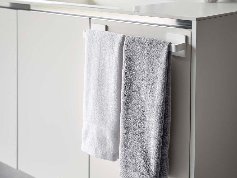 白色の【PLATE/プレート】フィルムフック タオルハンガー W36がバスルームのタイル壁に取り付けられており、タオルが掛けられている様子