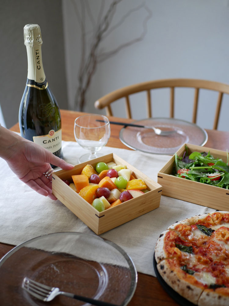 公長斎小菅の竹製二段重箱がテーブルウェアやボトル、フルーツと共に食卓に美しく配置された様子