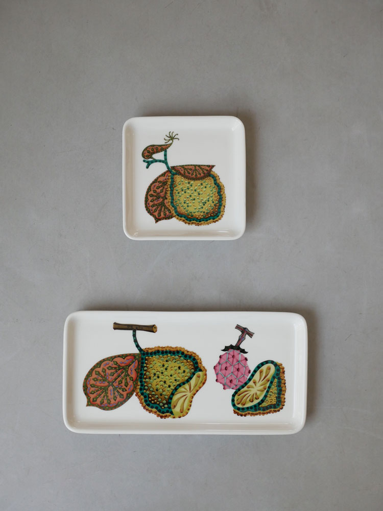 イッタラタイカシリーズの磁器製スクエアプレートとレクタングルプレートがトレーに並べられ、果物や自然食品が美しく盛り付けられている様子
