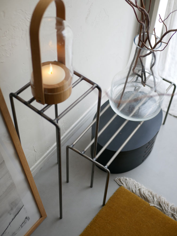 ウエストビレッジトーキョーのアイアンディスプレイプラントスタンドに花鉢とキャンドルホルダーが配置された木製フロア上の静物