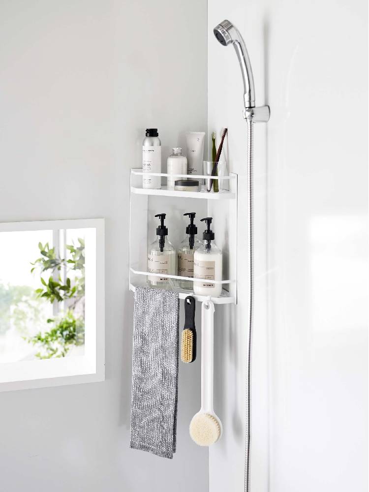 マグネット式タワーラックが浴室のコーナーに取り付けられ、シャンプーボトルやタオル、ソープディスペンサーが整然と配置されている様子