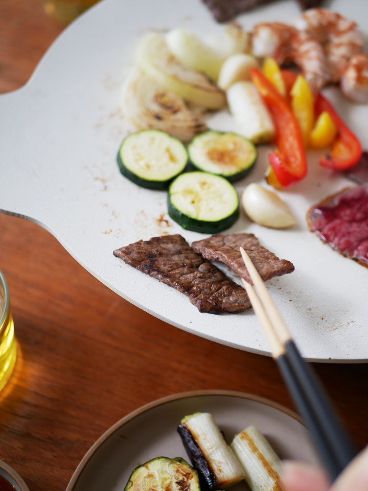 卓上IHクッキンググリドルで牛肉と野菜を調理し、食器が並べられたキッチンの様子