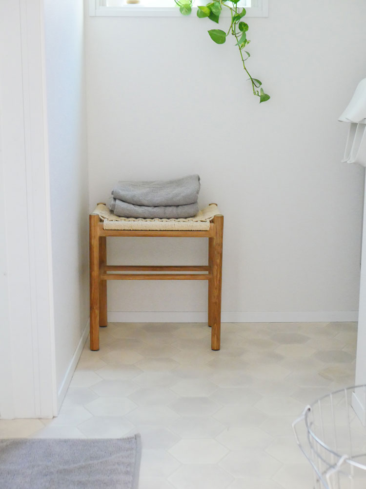 チーク無垢材とペーパーコードを使用したサンフラワーラタンHOKOSスツールが木目調の床上に配置されたナチュラルなインテリア