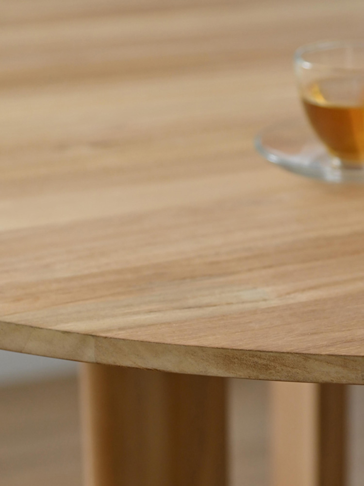 HOKOSサンフラワーラタン製チークラウンドダイニングテーブルの上に花束が美しく飾られている様子