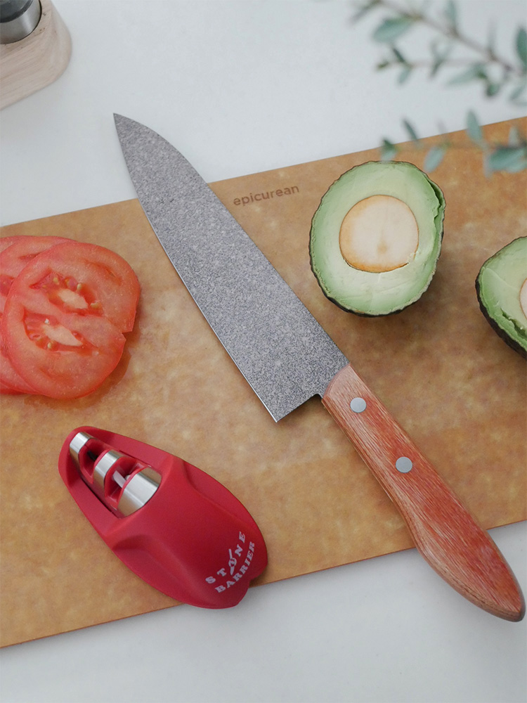 協和工業のスーパーストーンバリア包丁と専用シャープナーがカッティングボードと果物と共に配置されたキッチン用品の画像