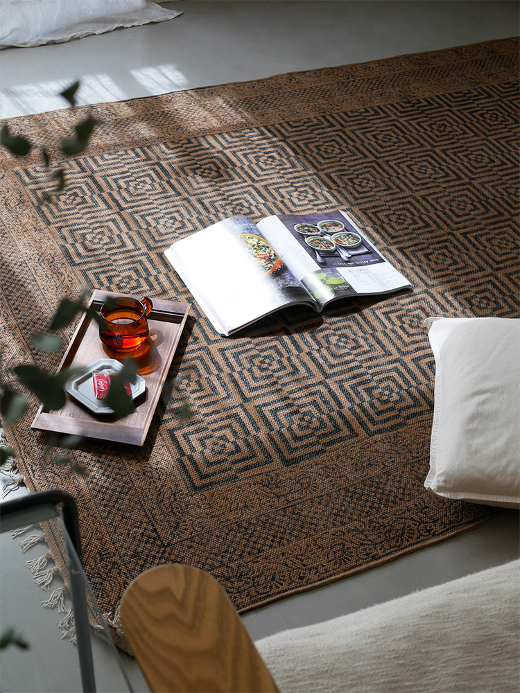 アデペシュ マニエール コットンラグ。木製フローリングに敷かれた茶色の織物マット