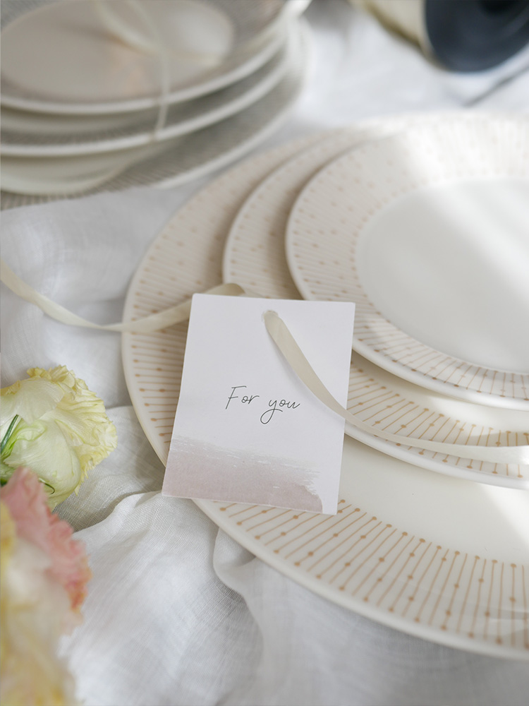 アラビア製マイニオの白磁プレートセット。直径15cm、19cm、25cmの異なるサイズのプレートが並んでおり、フリーザ、電子レンジ、オーブン、食洗機に対応可能。ベージュ色の特別なバックスタンプ入り。