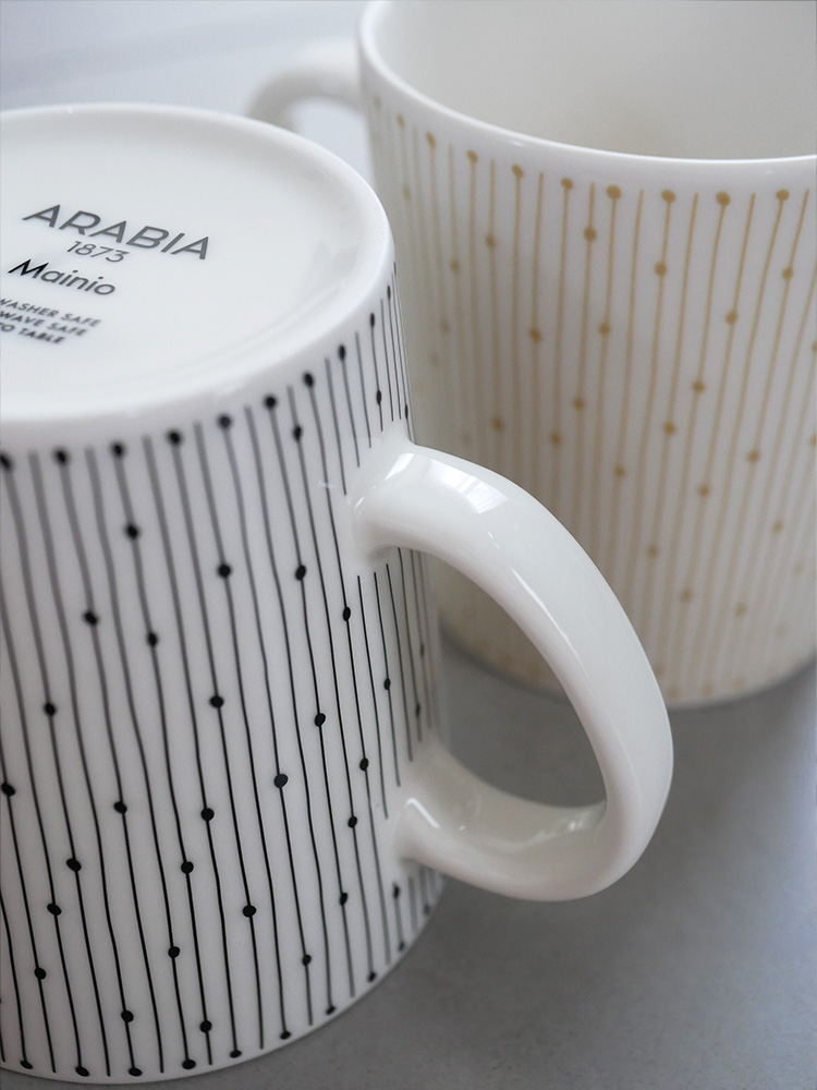 アラビア製マイニオ カップ&ソーサーセット。ベージュの磁器製カップとソーサーがテーブルに並んでいます