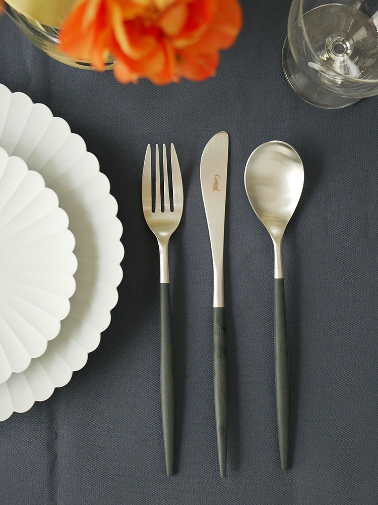 CutipolのMIOカトラリーセットのフォーク、スプーン、ナイフが白いテーブル上に整然と並べられた静物写真