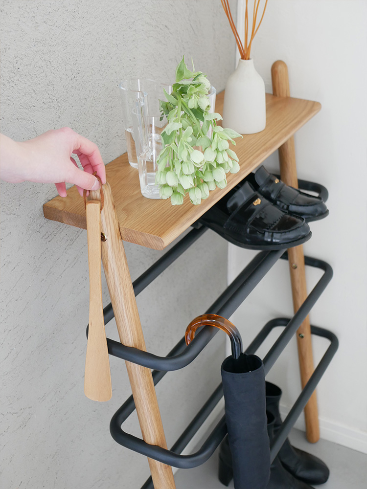 オーク無垢材とスチール製のSUK立て掛けシューズラックが壁に設置され、複数の棚やワインラック、観葉植物が配置された家庭用収納ユニットの様子