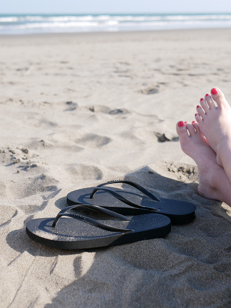 ビーチに置かれた黒色のフリップフロップサンダル