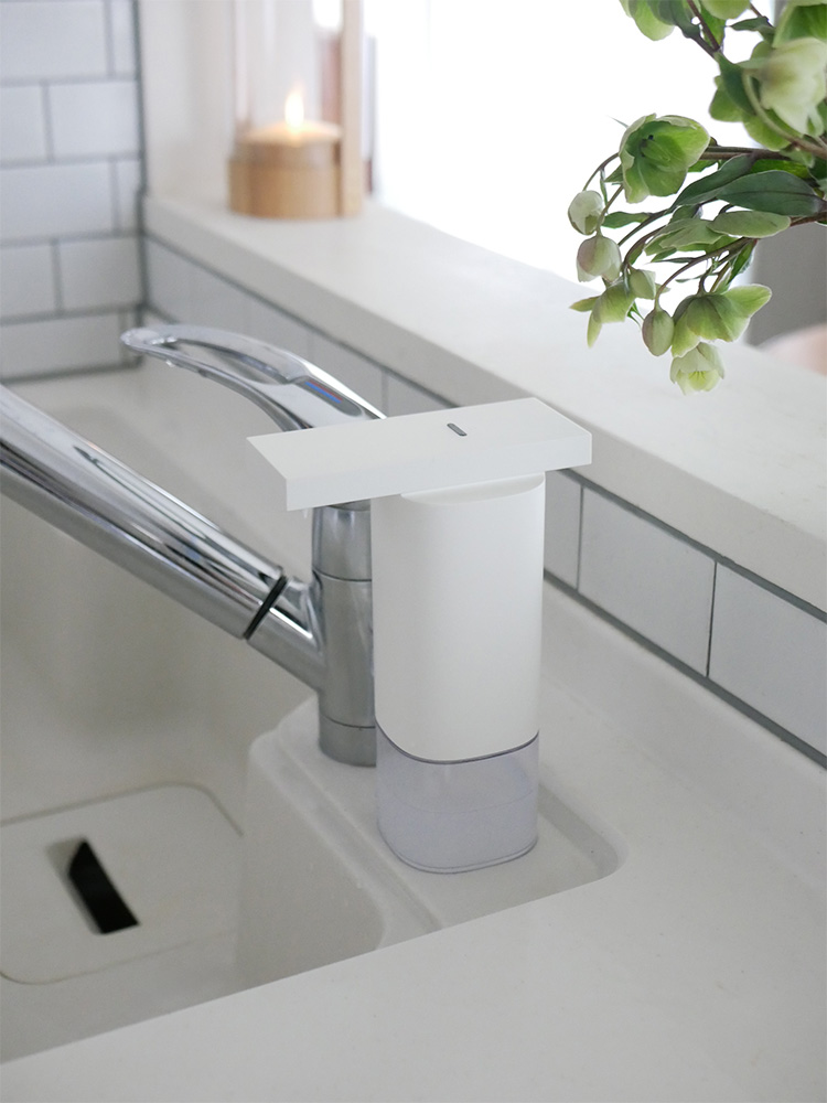 浴室の洗面台に設置されたプラスマイナスゼロオートディスペンサー。セラミック製のシンクに取り付けられ、アルコールや泡を自動で吐出するスマートなプラミングフィクスチャー。観葉植物と共にモダンなバスルーム空間を演出しています。