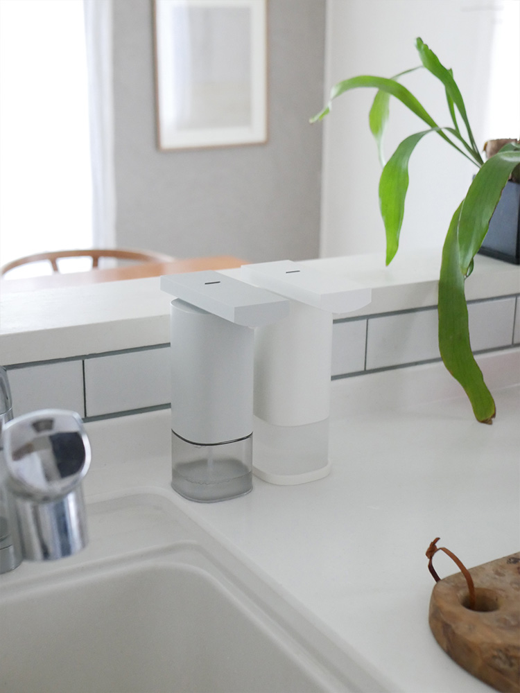 キッチンカウンターに設置されたプラスマイナスゼロ オートディスペンサーとシンク、蛇口、家庭用植物が配置されたシーン