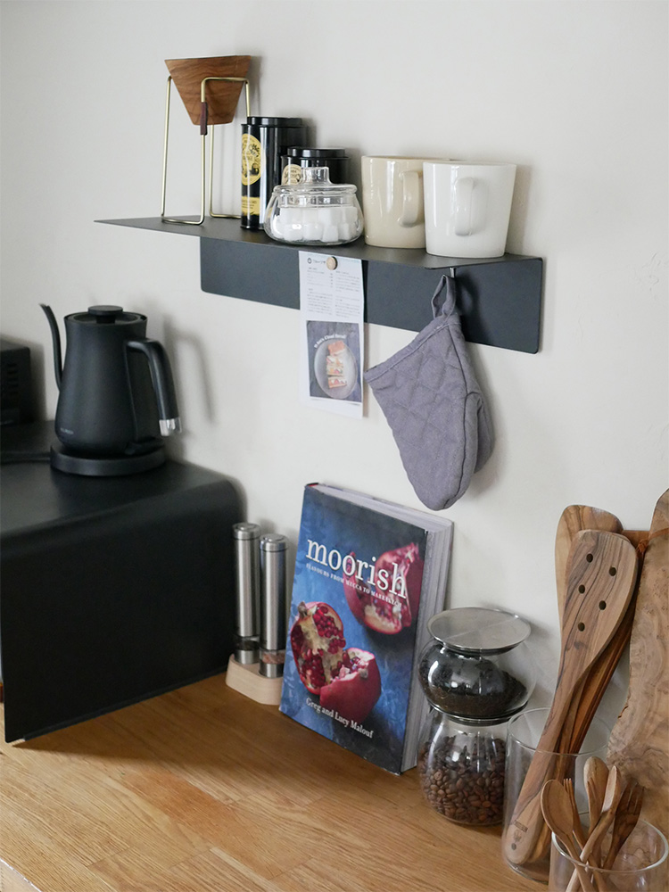 白色のタワーマグネット付きウォールラックに食器、カップ、キッチン用品、植物が整然と配置されている様子