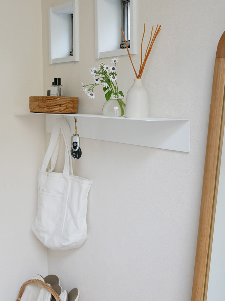 マグネット付きウォールラックが石膏ボードの壁に設置され、棚に観葉植物や花瓶、絵画、壁灯などが飾られている家庭用収納の様子