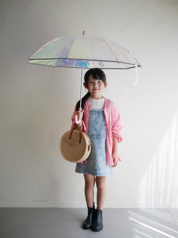 ピンクのシャイニーなキッズアンブレラを手に持ち、笑顔で立っている幼児の画像