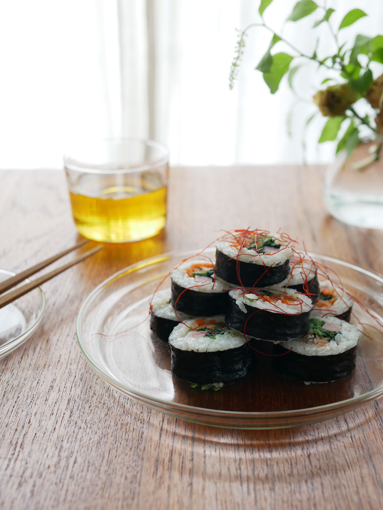 トレンドグラス イエナのホウケイ酸ガラス製Glass Plate上にカリフォルニアロールとガムバプが美しく盛り付けられた食卓の様子