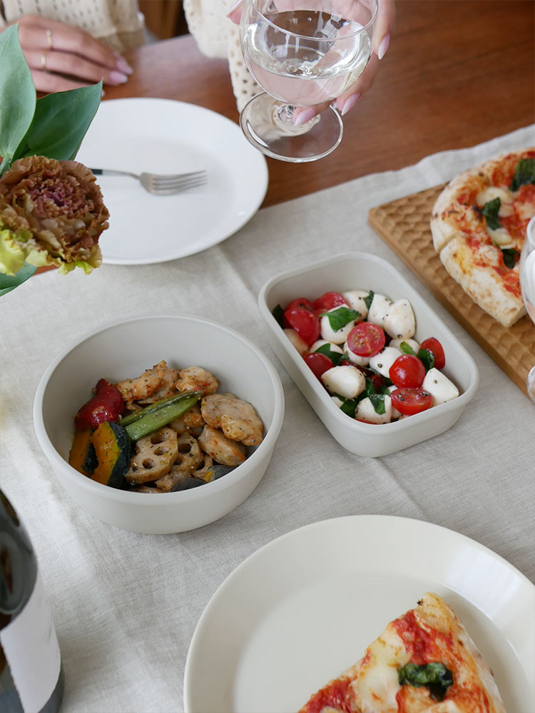 食卓に置かれたMEPAL（メパル）の汁漏れしにくいサーキュラマルチ保存容器と新鮮なサラダや野菜の盛り合わせ