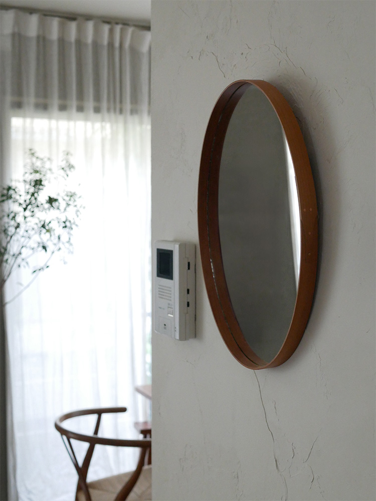 チェリー材製のアクシスシェーカーミラーが、明るい室内の壁に掛けられているインテリアデザインの画像