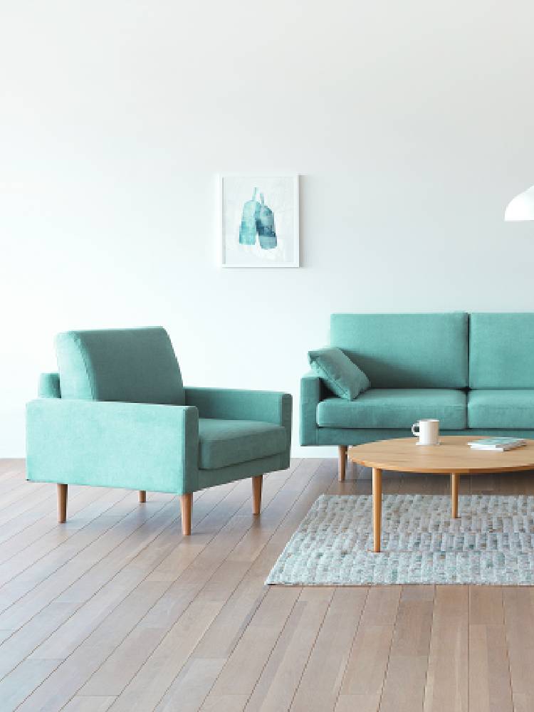 高野木工のLEOソファが配置されたモダンなリビングルーム。フローリングの床にクッションや椅子がアクセントとして置かれています。