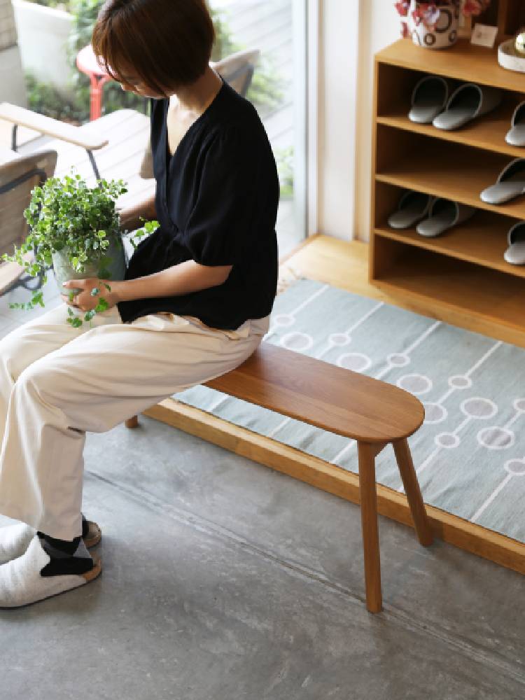 高野木工のホワイトオーク製RUBEワイドスツールが木製フローリングと室内植物と共に展示されている画像