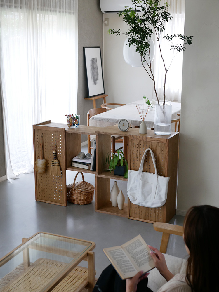 ノラの伸ばせて曲がるオープンシェルフ、天然木レッドオーク製の棚に花鉢やインテリア雑貨が飾られたリビングルームの一部