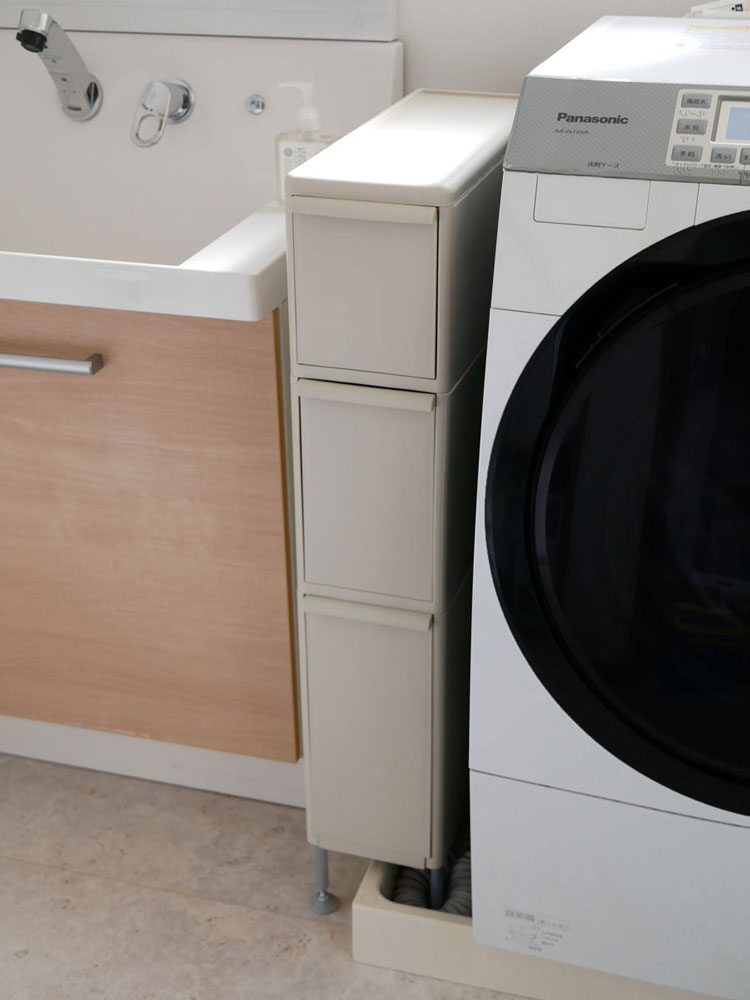 清潔な床にグレー色のアジャスター付きスリムストッカーと洗濯機が並ぶ室内の様子