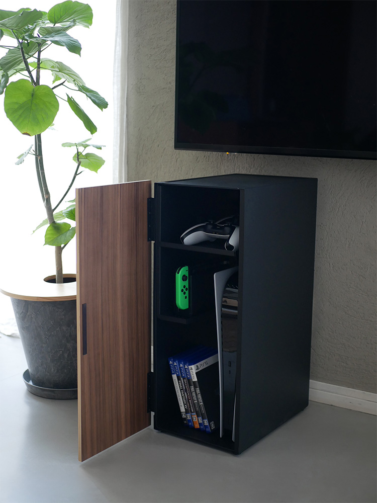 スチールと木製棚を備えたホワイトのタワー型ゲーム機収納ラックに、電子機器やガジェットが整然と配置されている