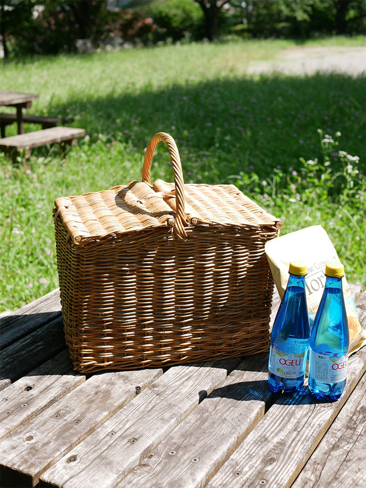 ラタンとレザーで作られたピクニッククーラーバスケットに果物や食材が詰められている様子