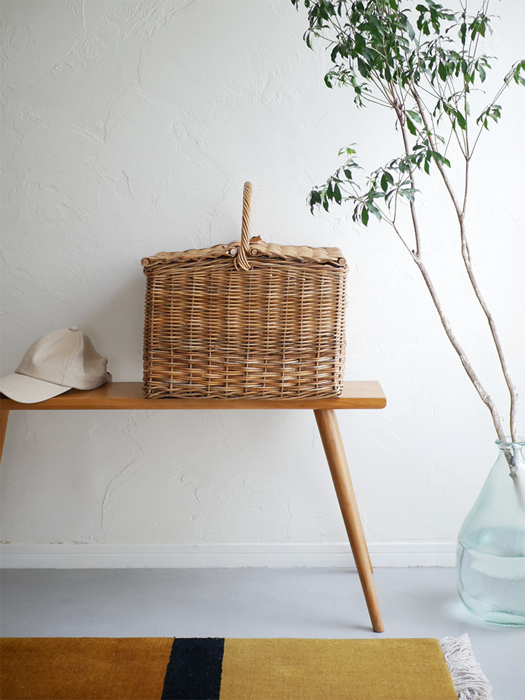 木材とラタンを使用したクレエのピクニッククーラーバスケットが花鉢やスツールと共にナチュラルな室内に配置されている様子