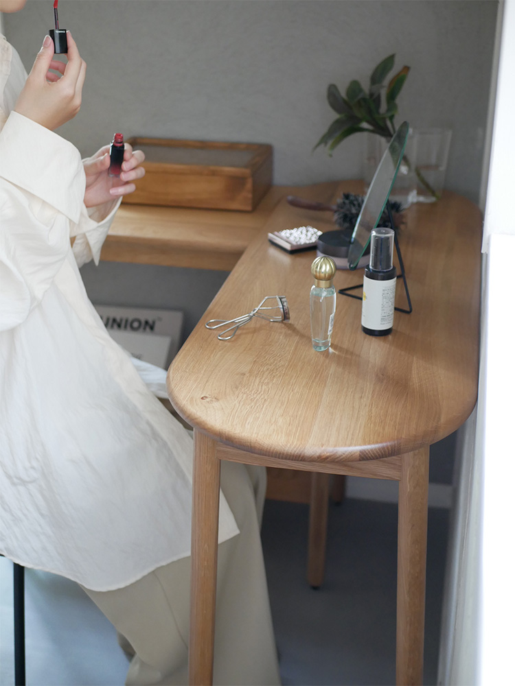 オーク無垢材で伸長可能なコンソールテーブルが、椅子やランプ、観葉植物と共にスタイリッシュな室内に配置されている様子