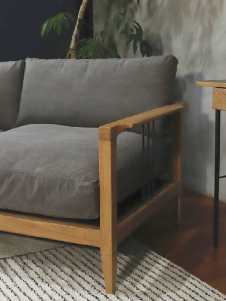 オーク無垢材で作られたadepecheのソロソファーが、クッションとスロー枕で彩られたリビングルームに設置されています。