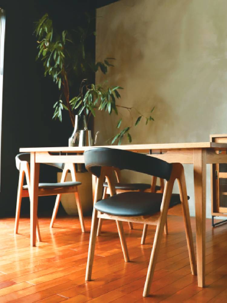 アデペシュ製cobakホールドアームチェア。オークまたはウォルナット無垢材のアームとウレタン座面を持つ木製家具が木張りの床の上に配置されています。