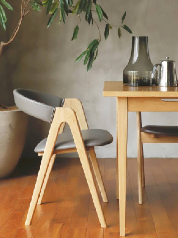 オーク無垢材とウレタン仕上げのアーム付きチェアが木製フローリングの上に配置されている