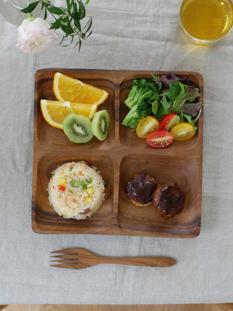 アカシア製の食器に盛り付けられた新鮮な果物と野菜がテーブルに配置されている様子