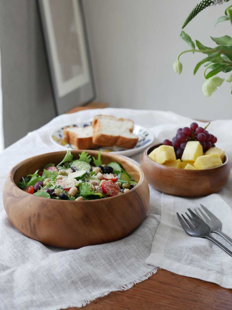 天然木アカシアの選べるやさしい食器セットと新鮮なサラダがテーブルに美しく配置されている様子