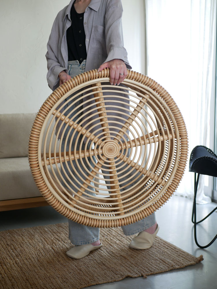 ラタンとガラスで仕上げられた【サンフラワーラタン】ローテーブルが木製フローリングの上に置かれている