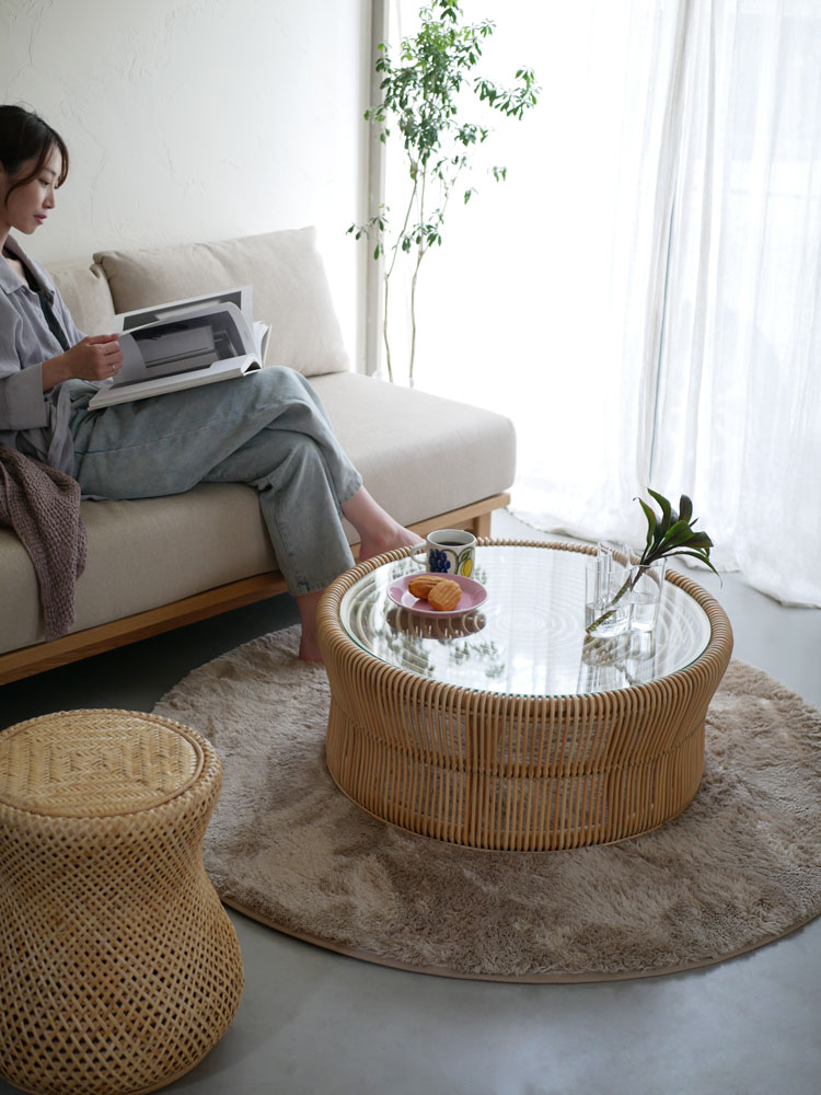 ラタンとガラス製のサンフラワーラタンローテーブルがリビングルームに配置されています