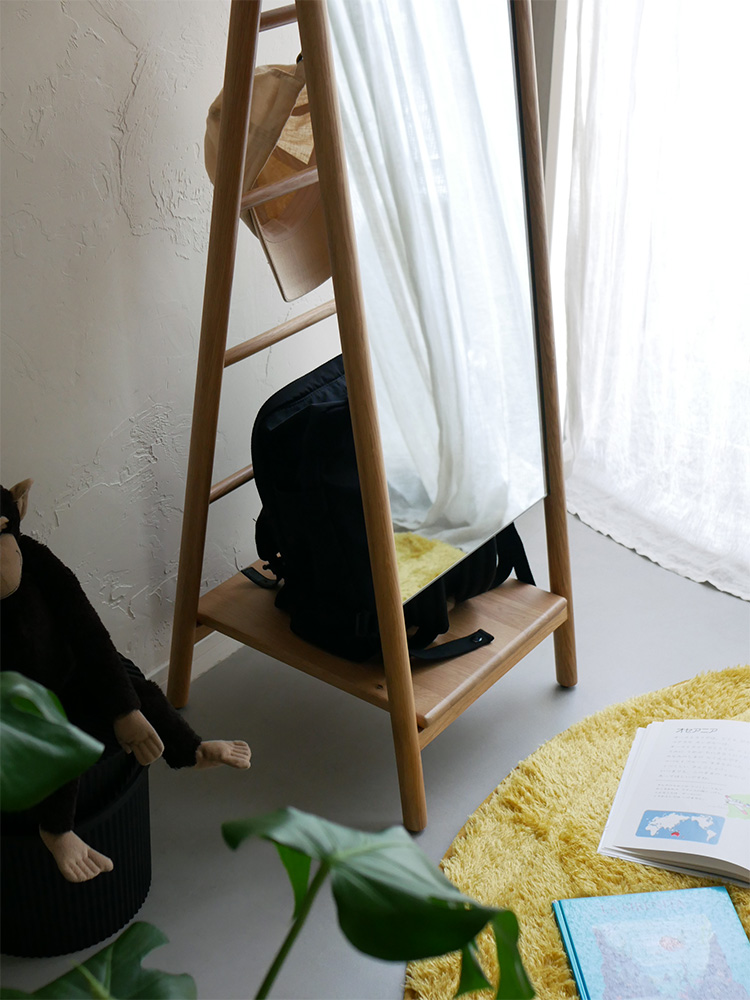 オーク材の収納機能付きスタンドミラー「SCALA」が木製の床の上に置かれ、観葉植物と共にインテリアとして配置されている様子