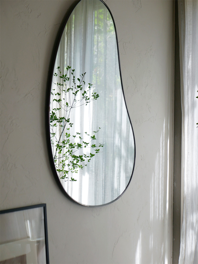 ブラスまたはチタニウム仕上げのアンブラ フーバ アーチド リー二ングミラーとオーバル型の照明器具が一体となった画像