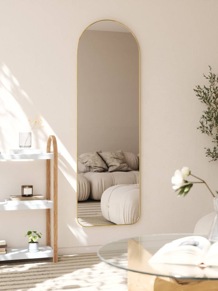 リビングルームに設置されたウムブラのフーバ アーチド リー二ングミラー。鏡の周囲にランプや観葉植物が配置され、空間を美しく演出しています。