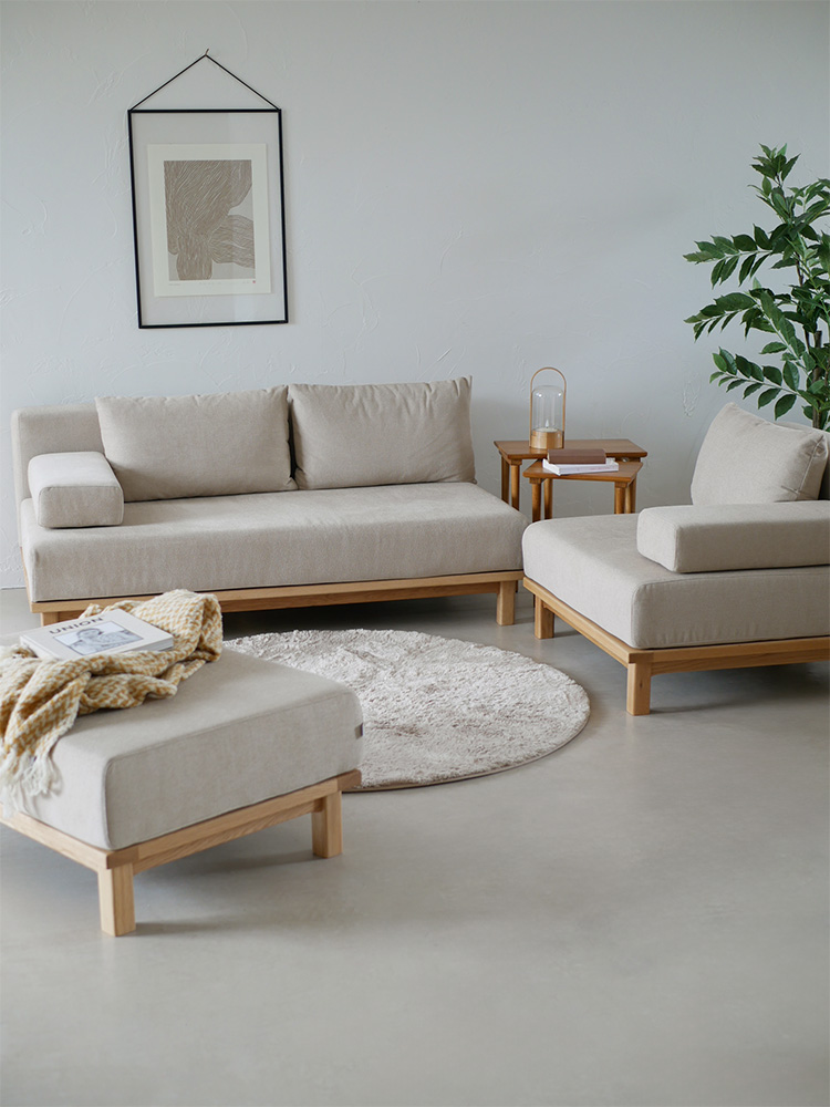 リビングルームの木製フローリングに配置された【SIEVE/シーブ】ゆったり座れるレクトユニットソファーとカラフルなクッション