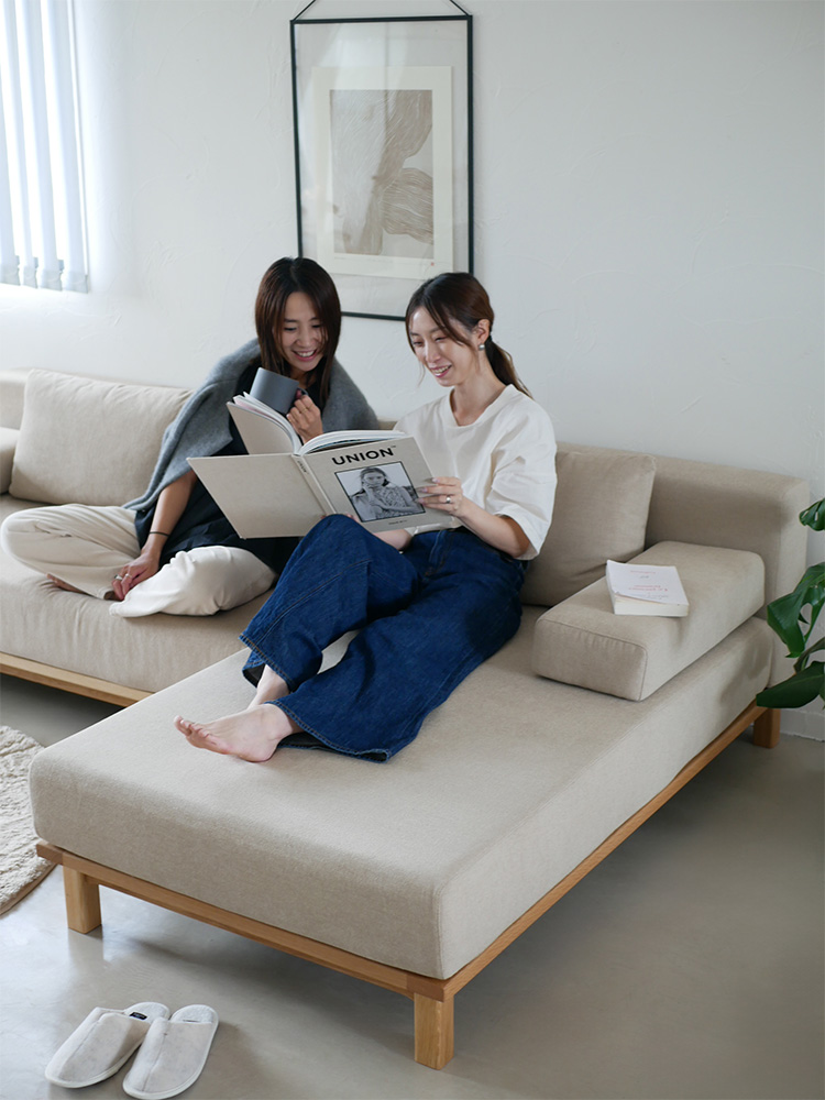 木製フローリングのリビングルームに配置された、シーブのゆったりと座れるファブリック製レクトユニットソファー。快適なクッションと複数の投げ枕が特徴的です。