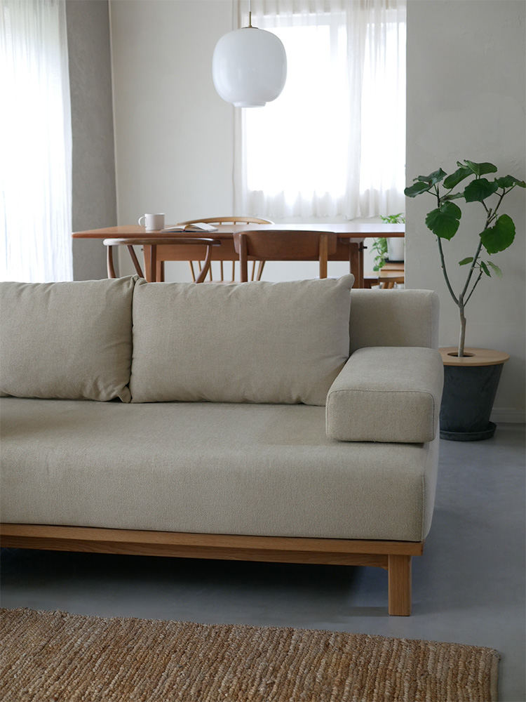 オーク無垢材フレームの【SIEVE/シーブ】ゆったり座れるレクトユニットソファーが木製フローリングのリビングルームに配置されています。