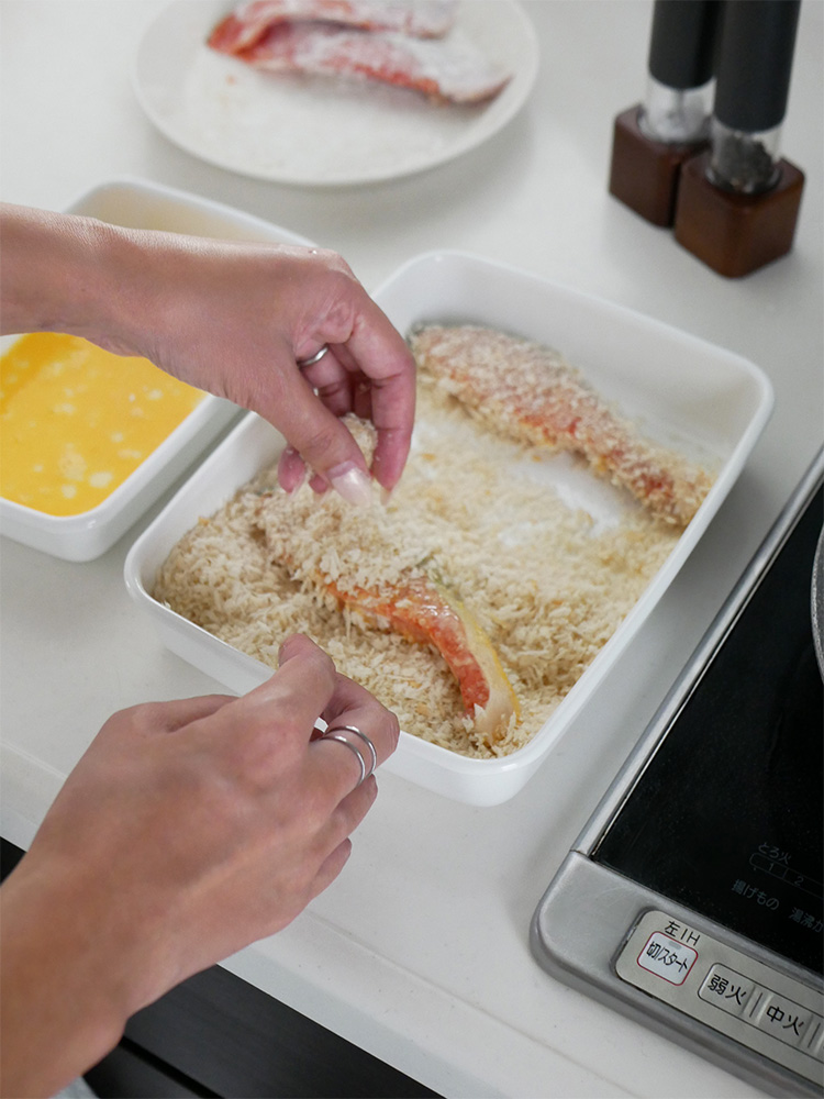 野田琺瑯 White Seriesのホーロー保存容器とシール蓋がキッチンテーブルに配置され、調理用品と共に使用されている様子