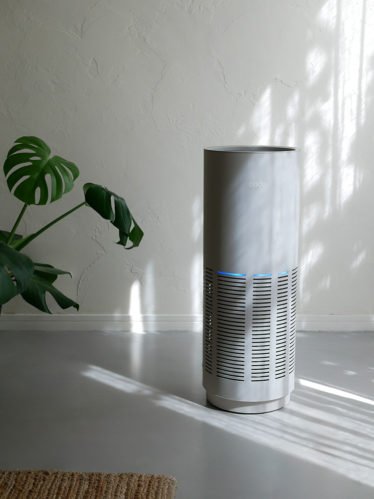 リビングルームの木製床に設置されたシルバー色のcado LEAF 320i 空気清浄機